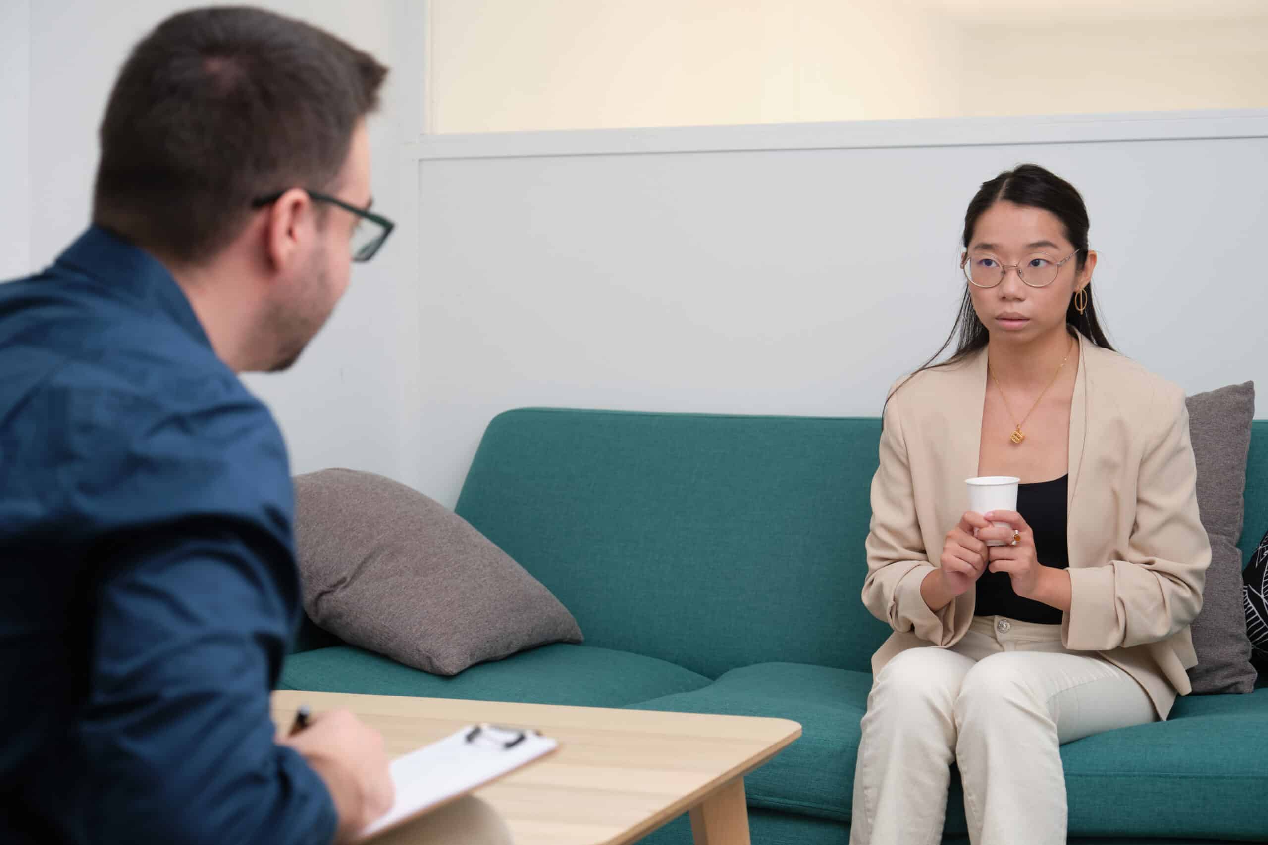 Caucasian male psychologist and asian woman patient at therapy. Mental health concept.