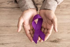 cropped view of senior man holding purple ribbon